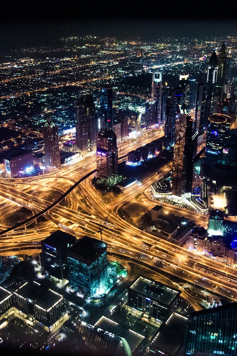 A stunning aerial view of Dubai's illuminated skyline at night, showcasing its modern architecture and busy roads.